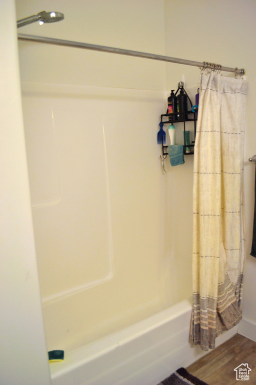 Bathroom featuring wood finished floors and shower / bathtub combination with curtain