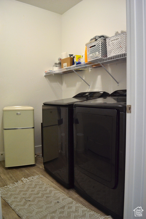 Laundry area with washer and clothes dryer and wood finished floors
