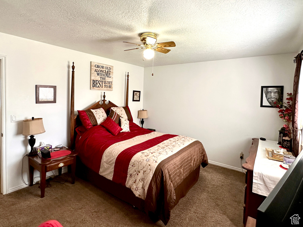 Carpeted bedroom with a ceiling fan and a textured ceiling