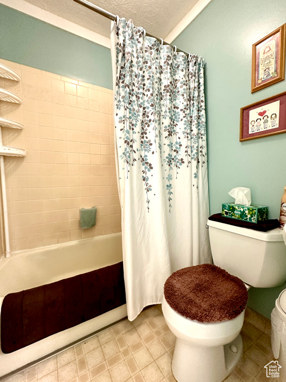 Full bath with shower / bath combo with shower curtain, a textured ceiling, and tile patterned floors