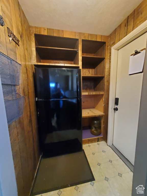 Kitchen featuring freestanding refrigerator, wooden walls, and open shelves