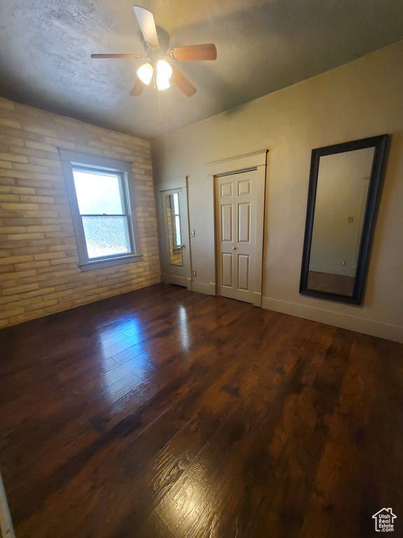 Foyer entrance featuring a ceiling fan, brick wall, and wood finished floors
