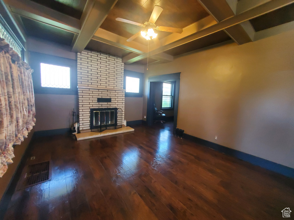 Unfurnished living room featuring coffered ceiling, wood finished floors, a brick fireplace, a ceiling fan, and beam ceiling