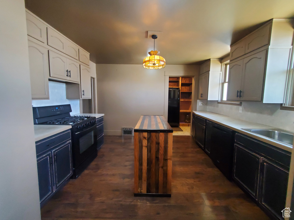 Kitchen featuring black appliances, dark wood finished floors, and light countertops