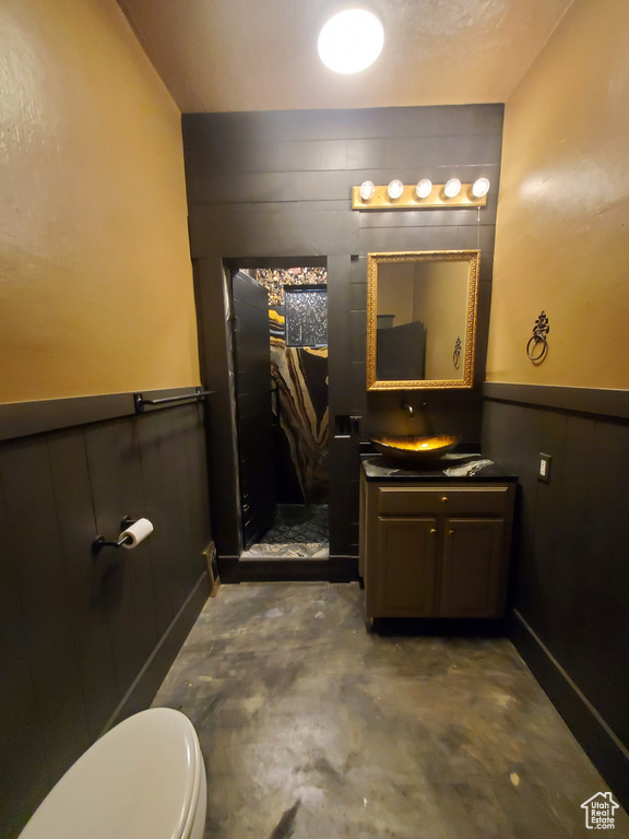 Bathroom featuring vanity, unfinished concrete flooring, a wainscoted wall, and wood walls