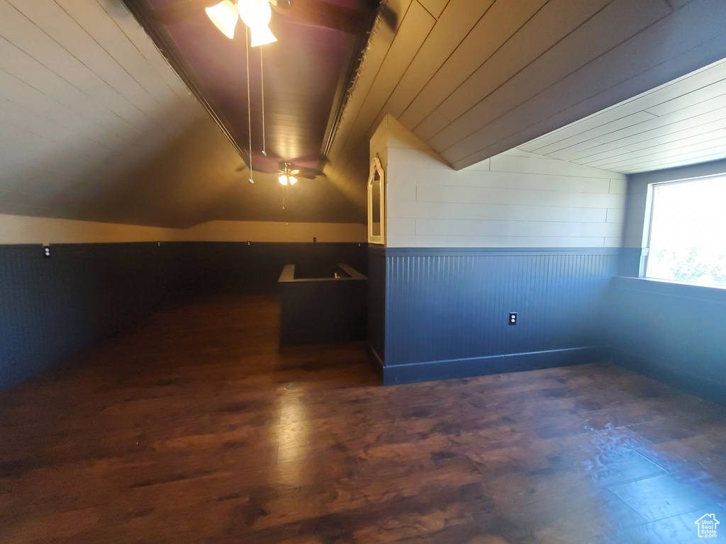 Additional living space featuring ceiling fan, wood finished floors, lofted ceiling, wainscoting, and wood walls