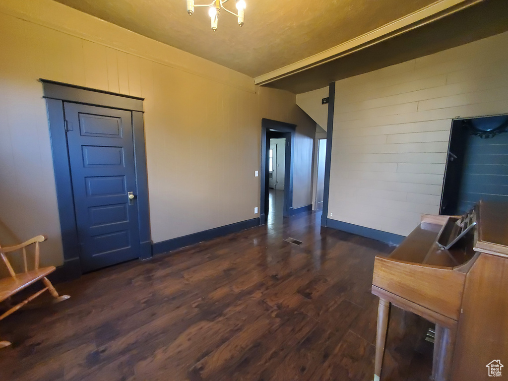 Unfurnished room featuring dark wood-style flooring and a chandelier