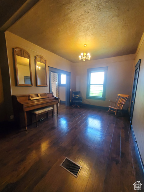 Interior space with dark wood-style flooring, a chandelier, and a textured ceiling