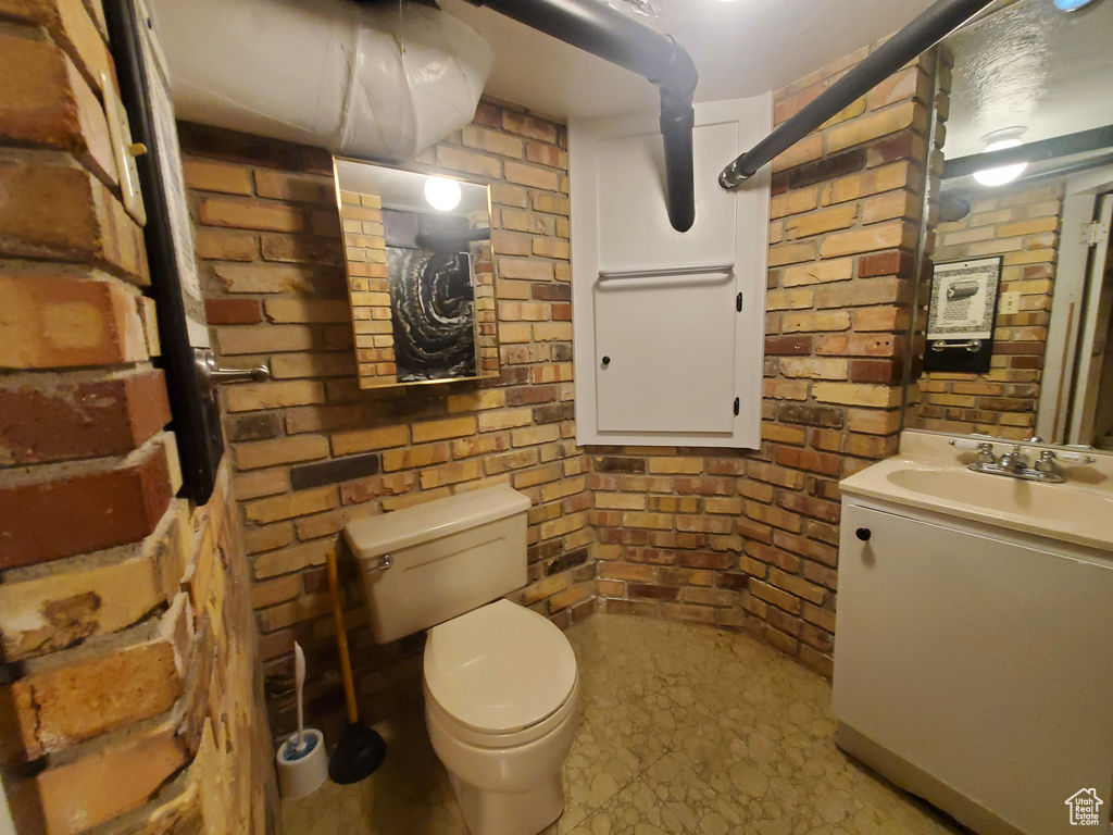 Half bathroom featuring vanity and brick wall