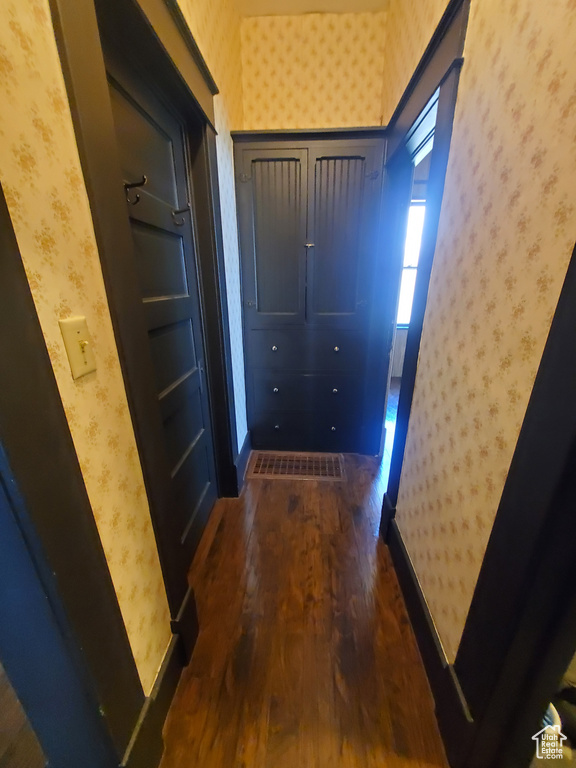 Corridor featuring wallpapered walls and dark wood-type flooring