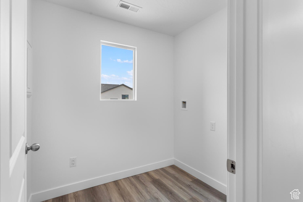 Washroom with wood finished floors and hookup for a washing machine