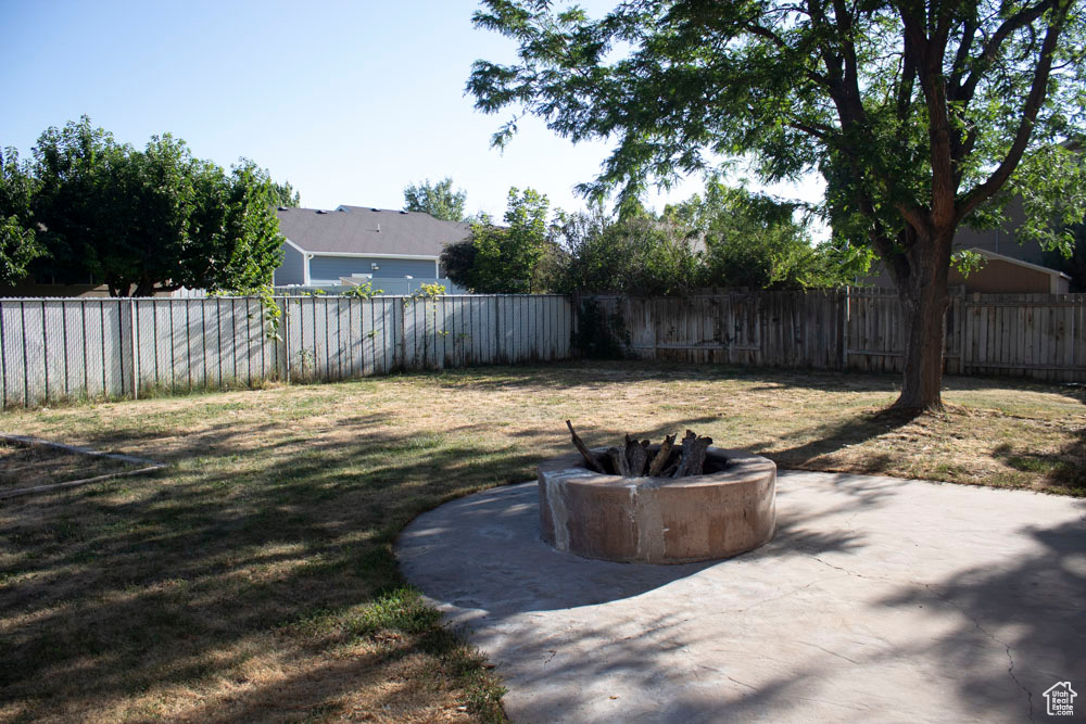 Fenced backyard featuring an outdoor fire pit and a patio area