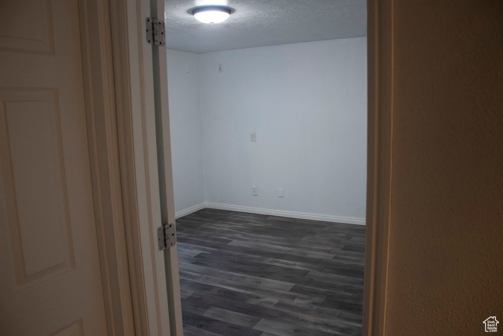 Unfurnished room featuring dark wood-style flooring and a textured ceiling