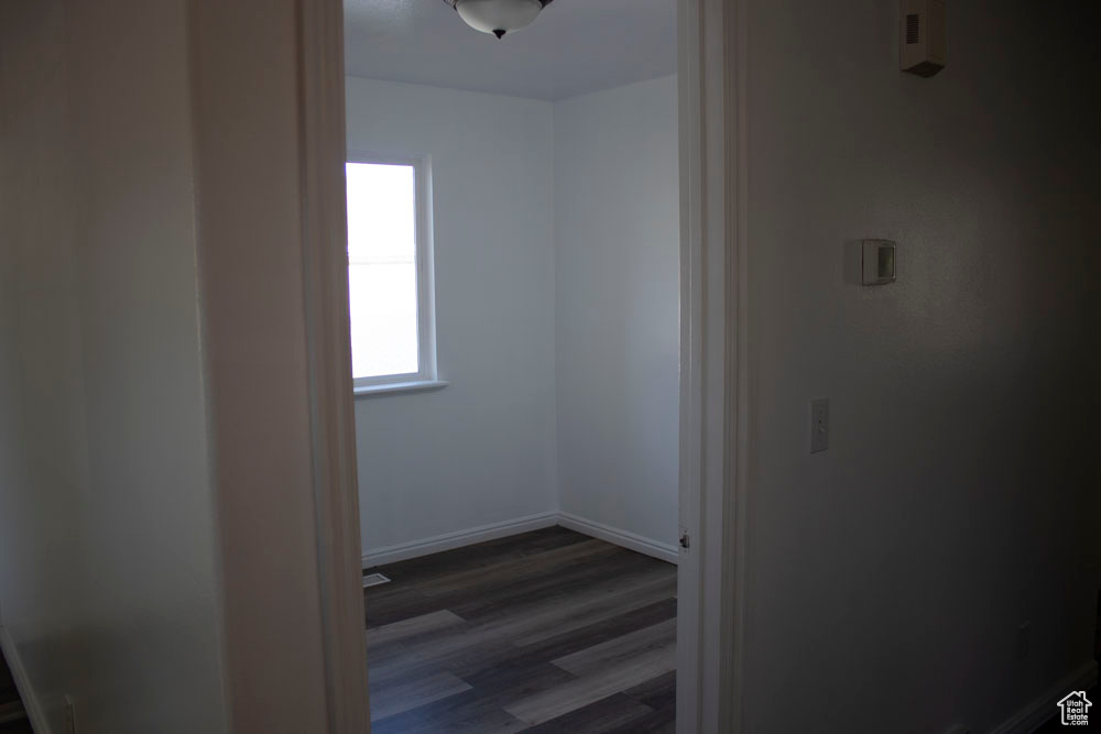 Hall with dark wood-style flooring and baseboards