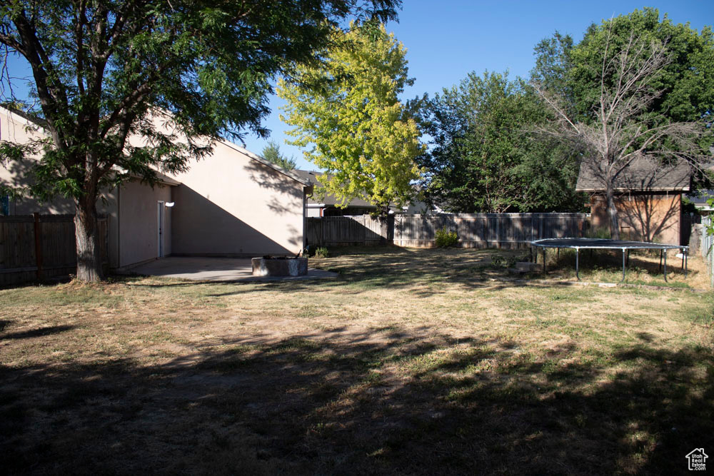 Fenced backyard featuring a trampoline