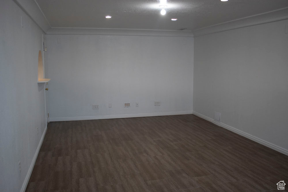 Spare room featuring dark wood finished floors, crown molding, and recessed lighting