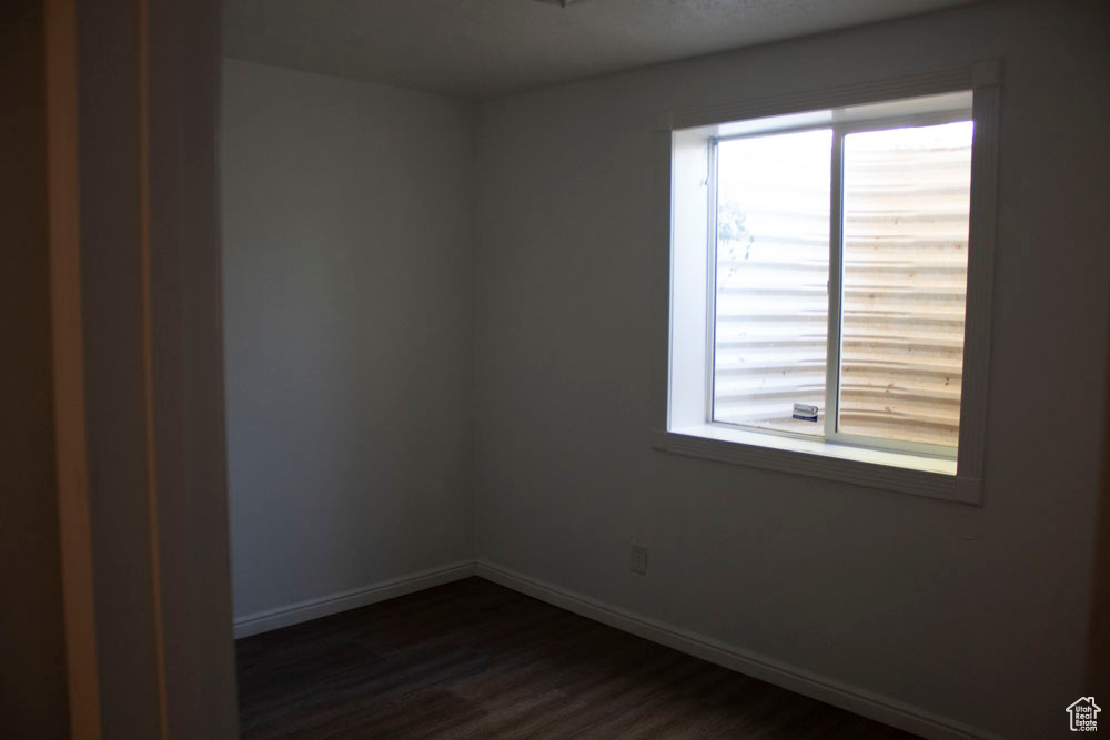 Unfurnished room with dark wood-style floors and healthy amount of natural light