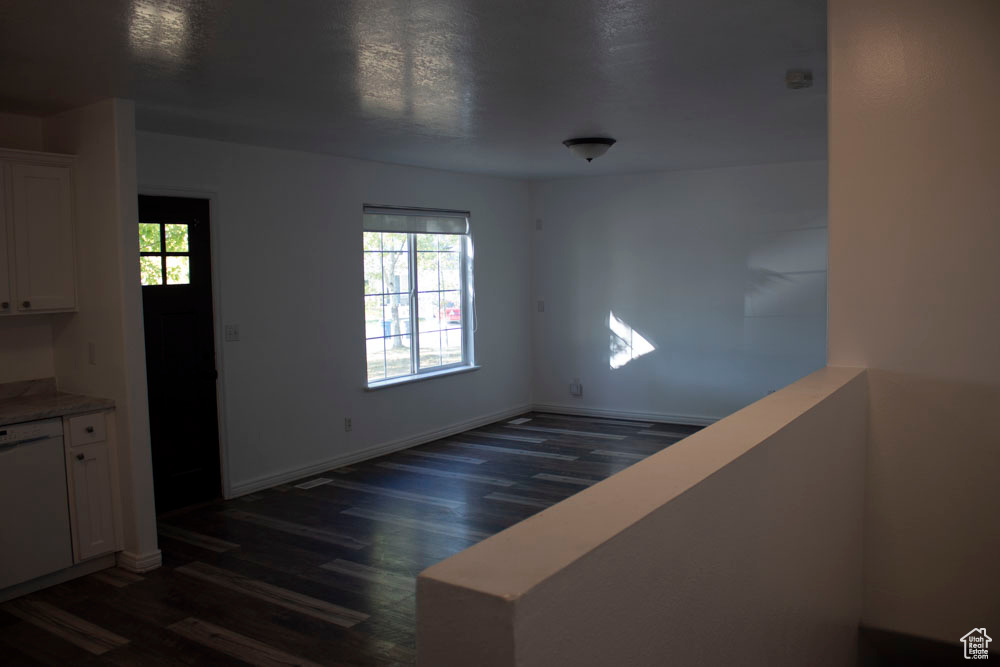Unfurnished dining area with dark wood-style floors and baseboards