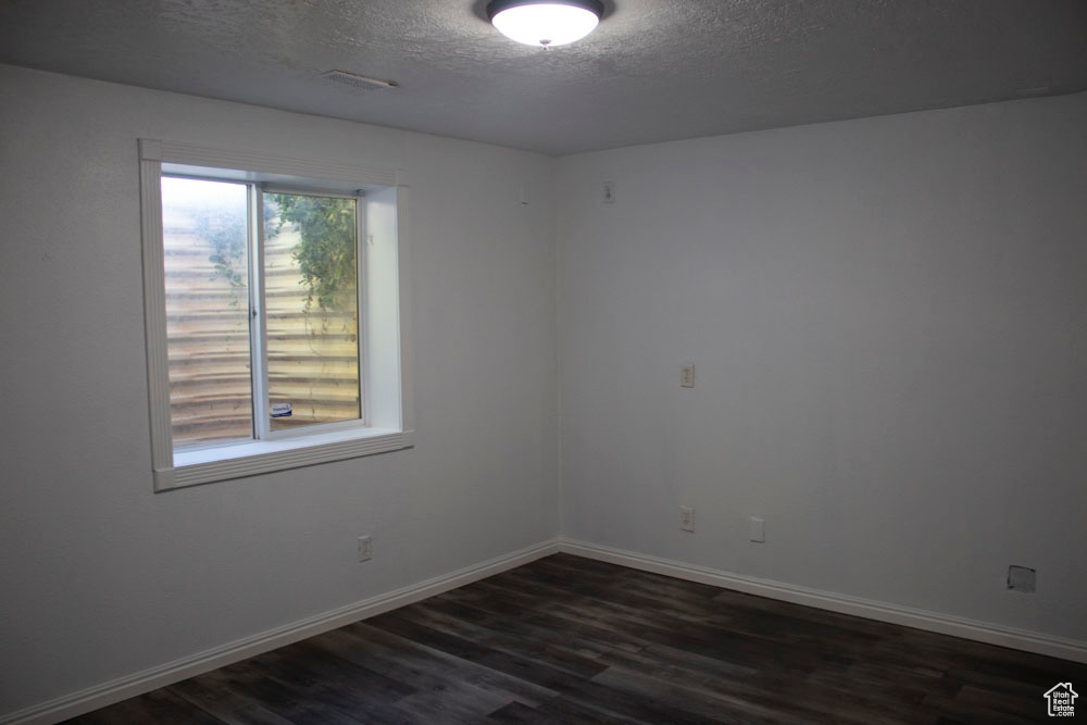 Spare room featuring a textured ceiling and dark wood-style floors