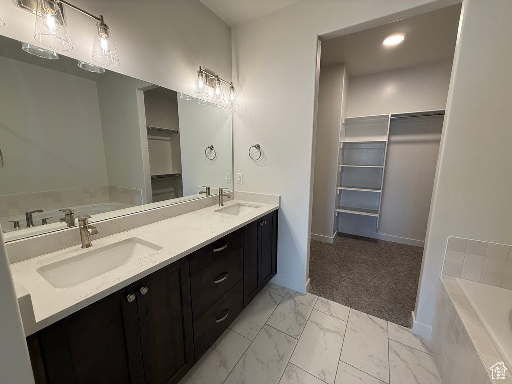 Bathroom featuring double vanity, a garden tub, a walk in closet, marble finish floors, and recessed lighting