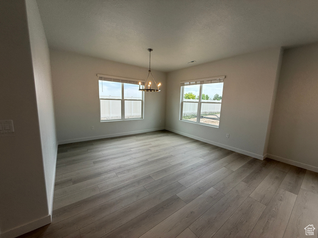 Empty room featuring a chandelier and wood finished floors
