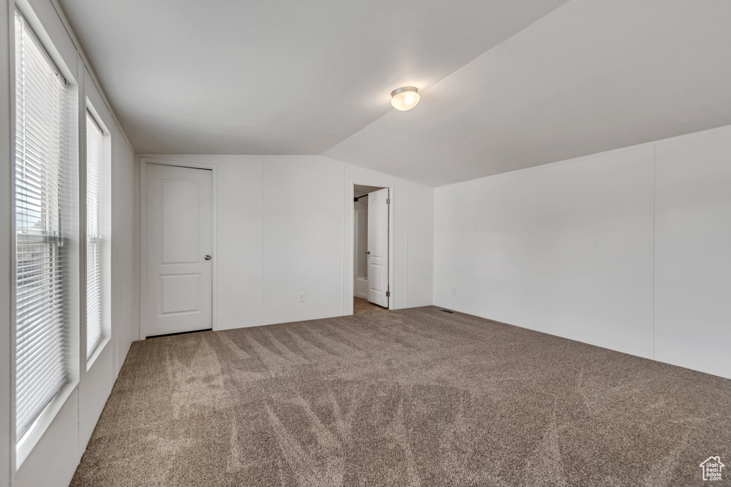 Unfurnished bedroom with carpet floors, vaulted ceiling, and multiple windows