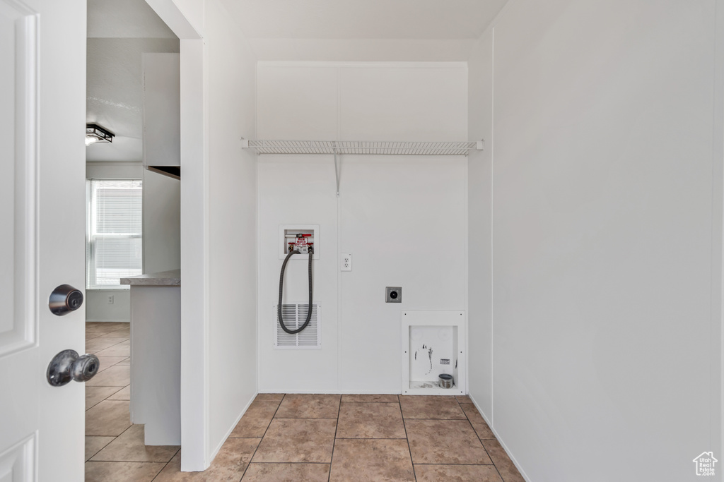 Laundry room featuring hookup for a washing machine, hookup for an electric dryer, and light tile patterned floors