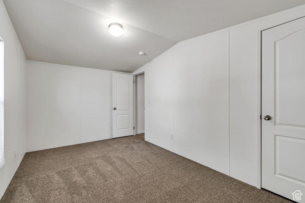 Carpeted empty room featuring vaulted ceiling