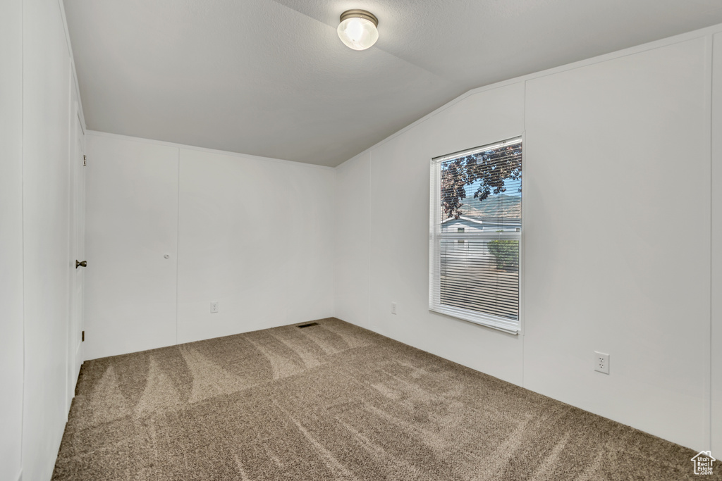 Unfurnished room with carpet flooring and lofted ceiling