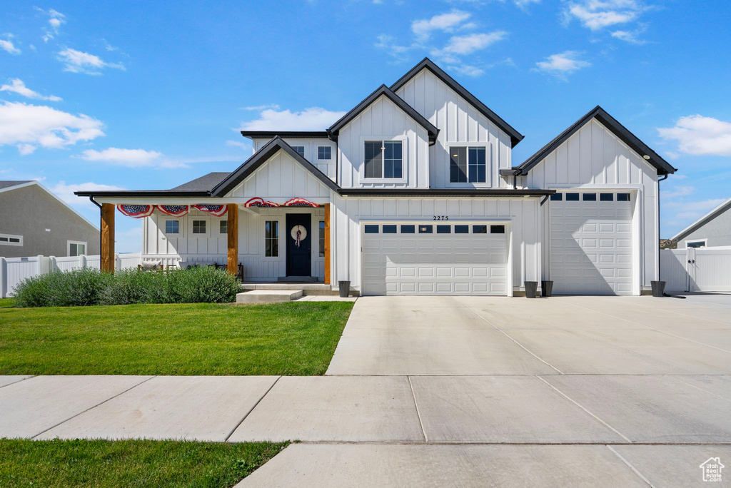 Modern farmhouse featuring board and batten siding, concrete driveway, a garage, an attached garage, and covered porch
