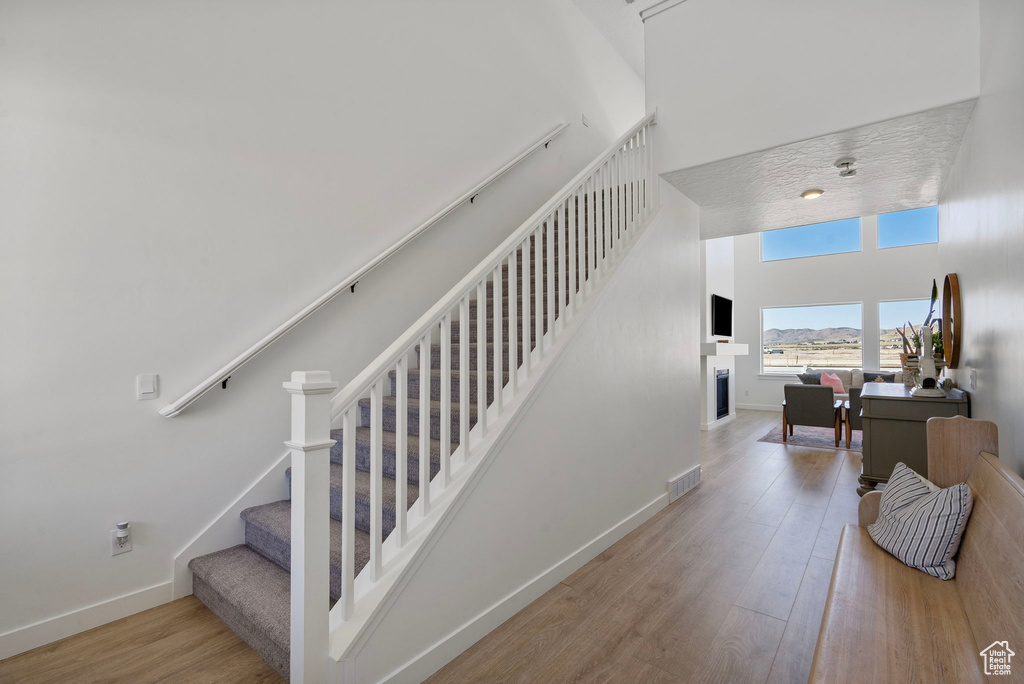 Staircase featuring a towering ceiling and wood finished floors