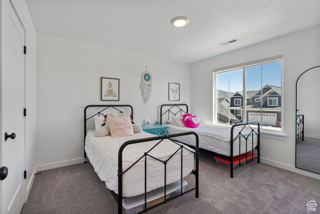 Carpeted bedroom featuring baseboards and a textured ceiling