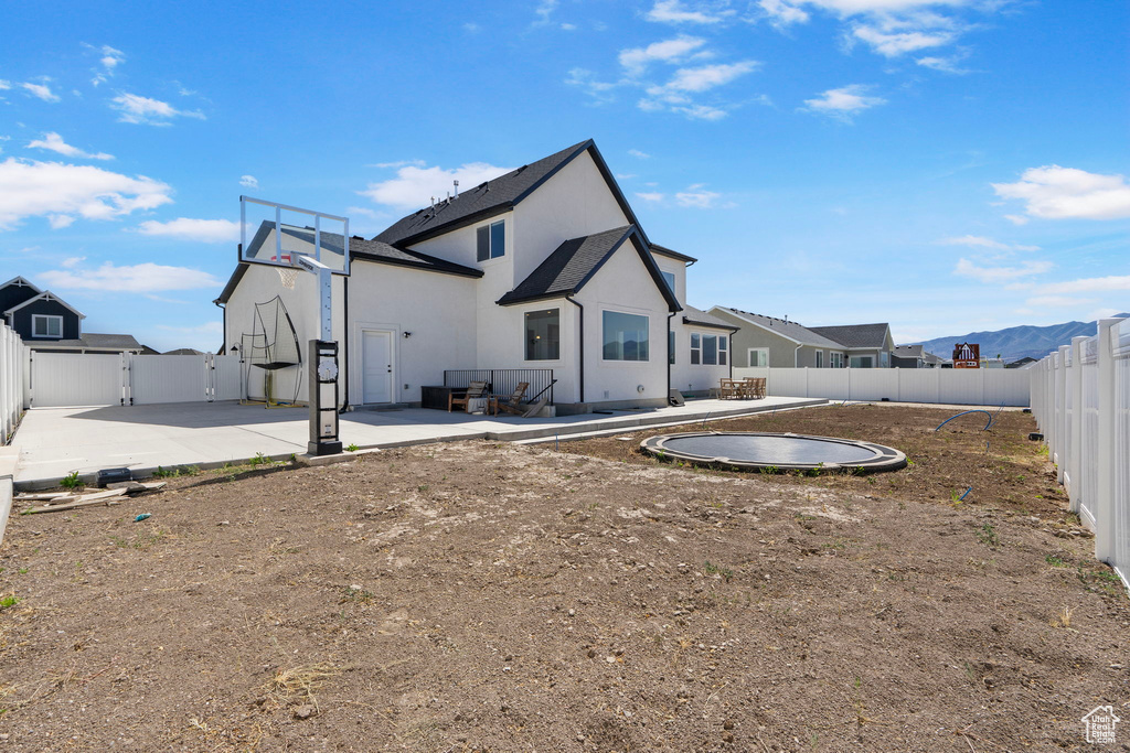 Back of property featuring a fenced backyard, a gate, a patio, and stucco siding