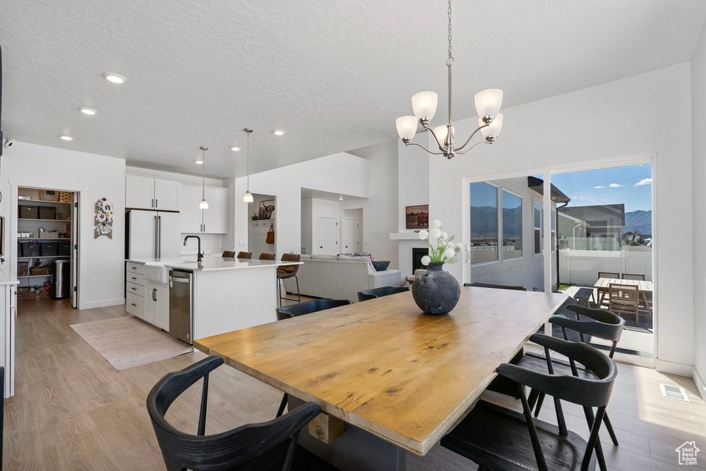 Dining area with light wood-style flooring, a chandelier, recessed lighting, and a textured ceiling