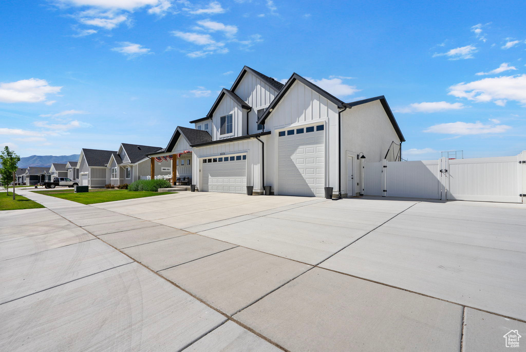 View of side of property with a gate, driveway, a residential view, board and batten siding, and an attached garage