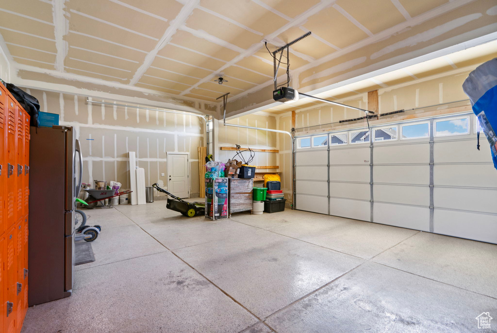 Garage featuring a garage door opener and freestanding refrigerator