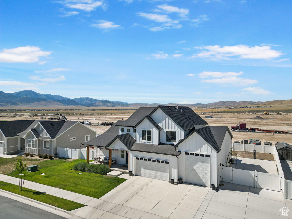 Modern farmhouse featuring a gate, board and batten siding, a mountain view, and driveway