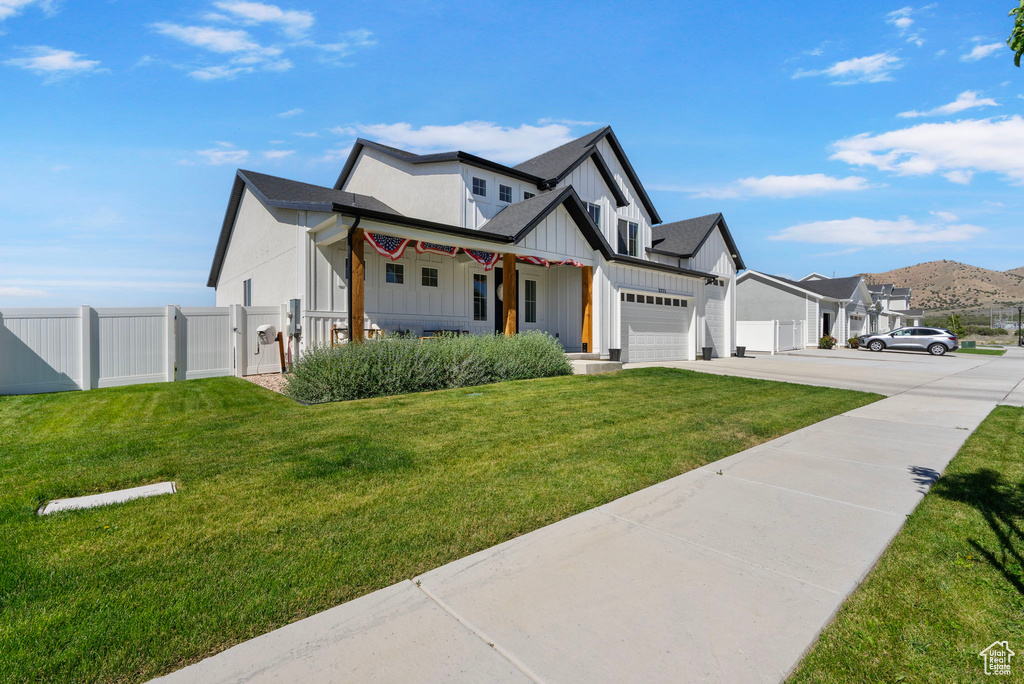 View of front of home featuring board and batten siding, concrete driveway, a gate, a garage, and a porch
