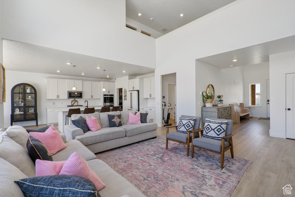 Living room with light wood finished floors, recessed lighting, and a towering ceiling