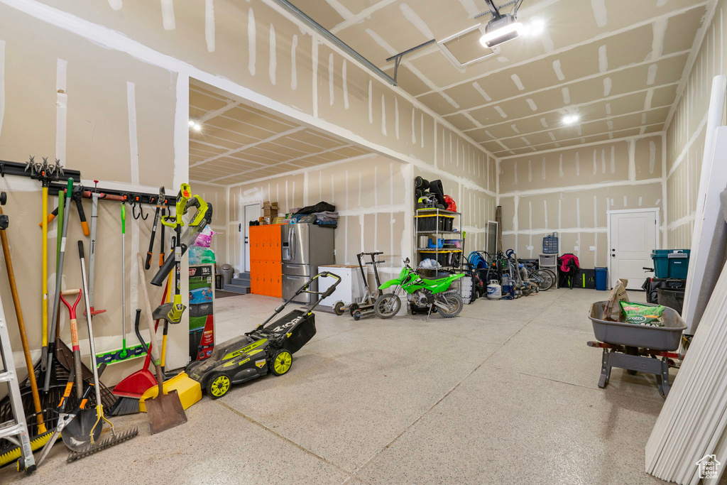 Garage with a garage door opener and stainless steel refrigerator with ice dispenser