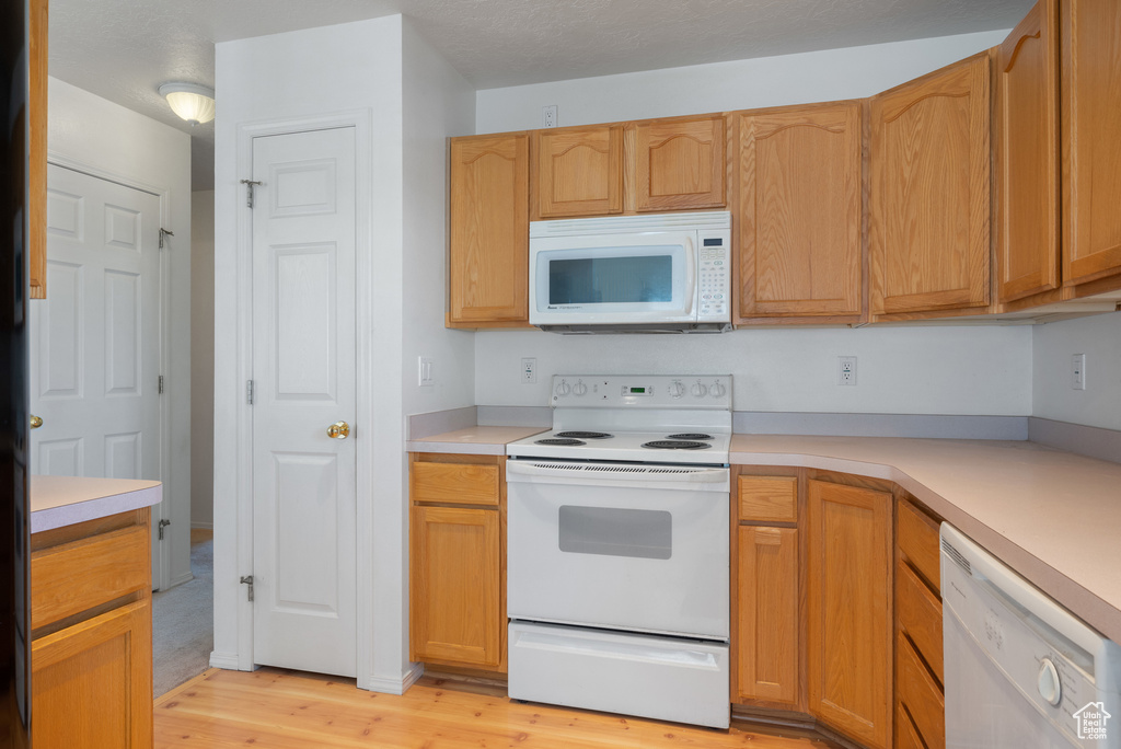 Kitchen featuring white appliances, light wood-type flooring, and light countertops