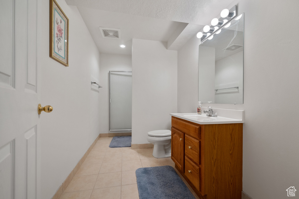 Bathroom featuring vanity, a stall shower, tile patterned floors, and recessed lighting