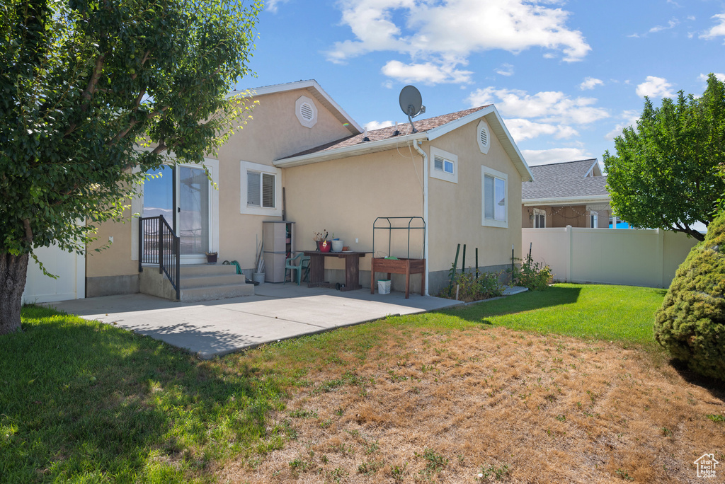 Rear view of house with stucco siding and a patio