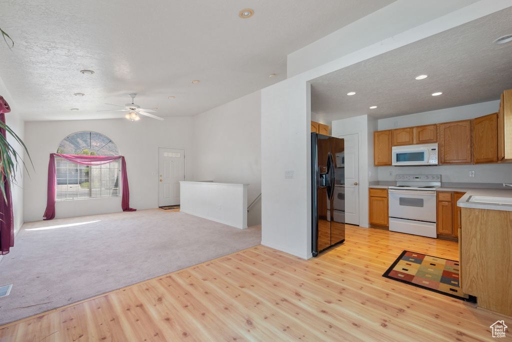 Kitchen featuring open floor plan, white appliances, light wood-type flooring, light countertops, and recessed lighting