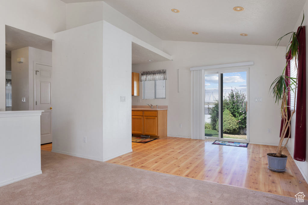 Carpeted entrance foyer with vaulted ceiling and baseboards