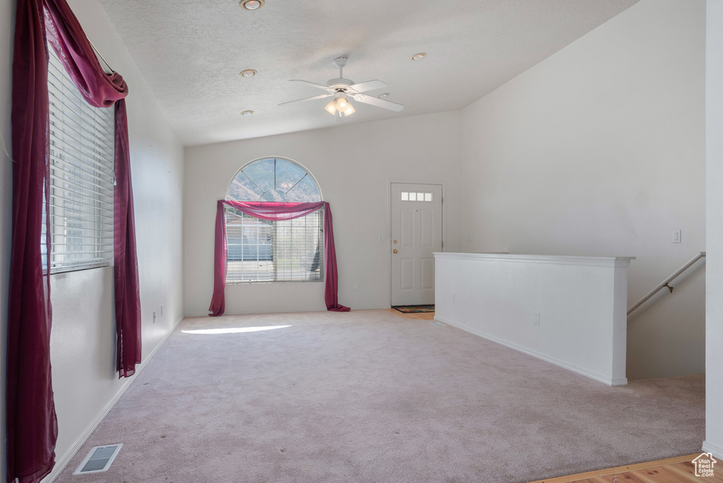 Spare room featuring carpet floors, vaulted ceiling, and a ceiling fan