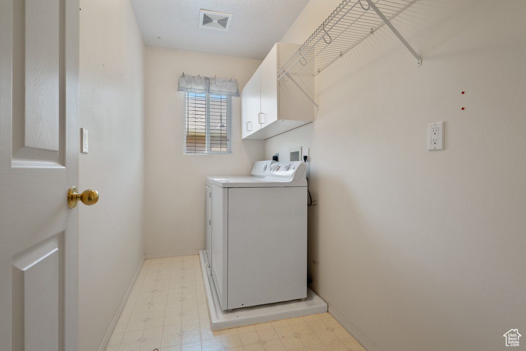 Washroom with cabinet space, separate washer and dryer, and light floors