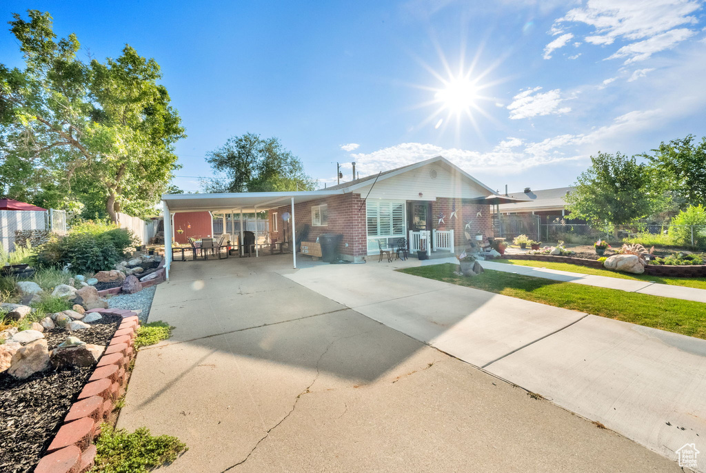 View of front of house featuring concrete driveway, an attached carport, and brick siding