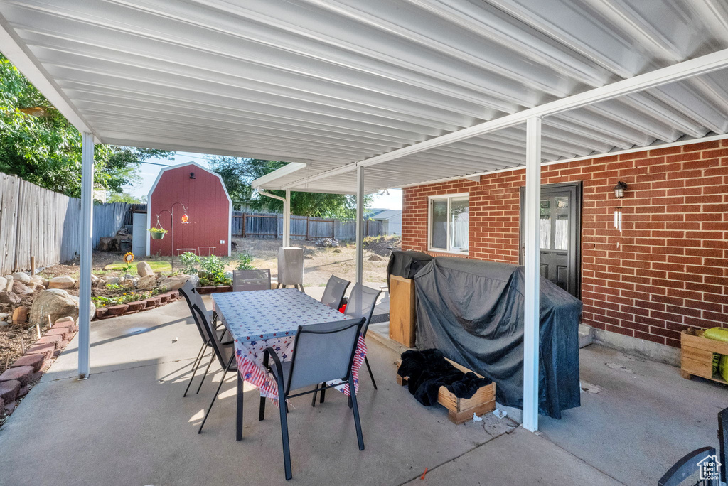 Fenced backyard with a storage shed, outdoor dining area, a patio area, and grilling area