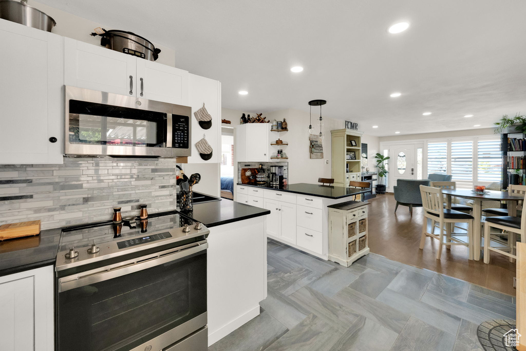 Kitchen with appliances with stainless steel finishes, dark countertops, open shelves, decorative backsplash, and recessed lighting